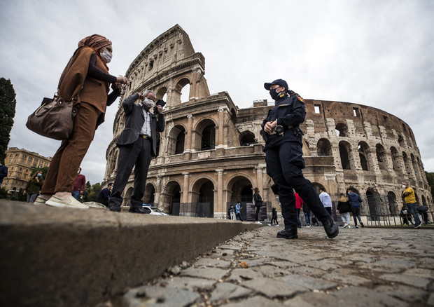 Un poliziotto con alcuni turisti davanti al Colosseo © ANSA