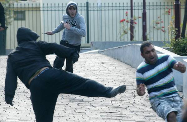 Greek racists, one of them (C) holding a knife, attacking a migrant (R) in the center of Athens (archive photo)