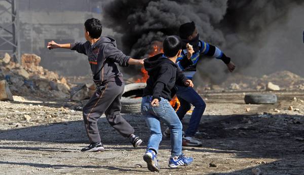 Ragazzi palestinesi lanciano pietre contro i militari israeliai a Kafr Kadum