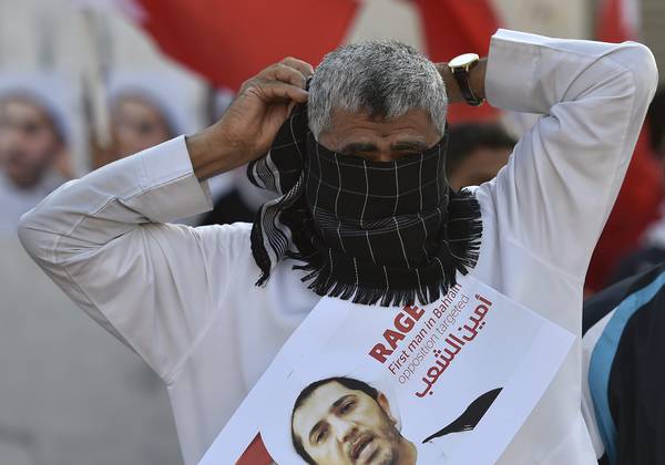 Un manifestante in Bahrein si copre il volto durante una protesta per l'arresto del leader dell'opposizione Sali Salman