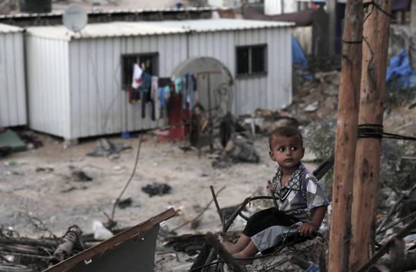 Un bambino palestinese tra i resti della sua casa distrutta durante i raid aerei israeliani dell'estate scorsa nella Striscia di Gaza