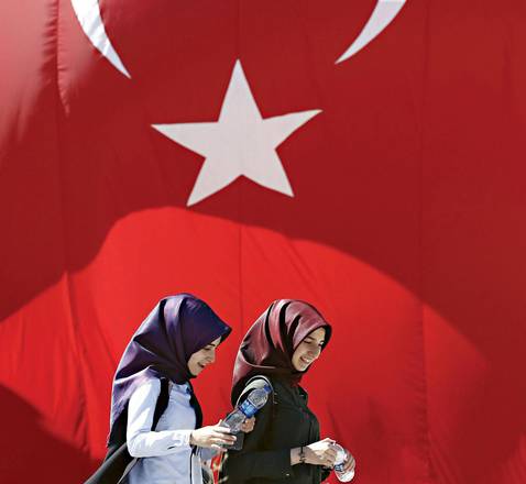 due giovani donne turche camminano davanti ad una bandiera turca all'Università di Istanbul (foto ANSA)