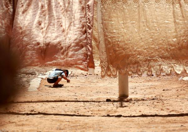 Un piccolo rifugiato siriano gioca vicino al bucato steso in un campo profughi in Giordania (archivio).