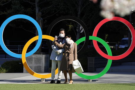 Un selfie tra gli anelli olimpici davanti al quartier generale del Comitato olimpico giapponese a Tokyo © EPA