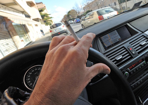 Un uomo fuma una sigaretta guidando l'auto © ANSA