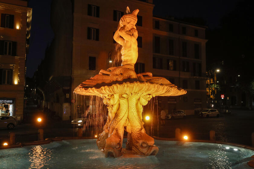 The Tritone 's Fountain is illuminated in orange - ALL RIGHTS RESERVED