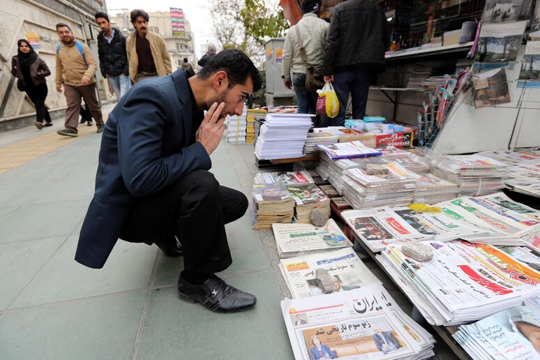 Un iraniano legge i giornali esposti davanti a una edicola a Teheran -     RIPRODUZIONE RISERVATA