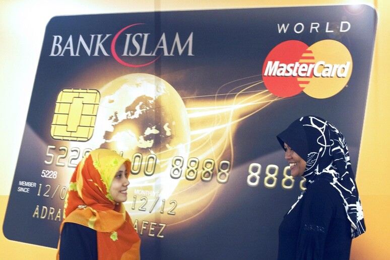 Donne malesi davanti ad un poster della Islamic Bank Mastercard a Kuala Lumpur, nel 2009 -     RIPRODUZIONE RISERVATA