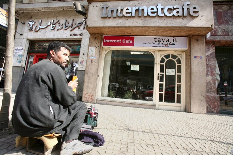 Un pulisciscarpe fuori da un internet cafè al Cairo -     RIPRODUZIONE RISERVATA