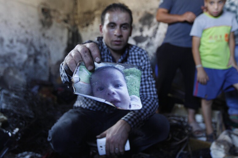 Un parente mostra la foto del piccolo Ali Dawabsheh ucciso la notte scorsa nell 'incendio doloso della sua casa nel villaggio di Duma, vicino Nablus © ANSA/AP