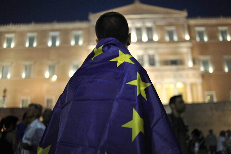 Un manifestante pro-euro avvolto nella bandiera dell 'Ue davanti al Parlamento di Atene -     RIPRODUZIONE RISERVATA