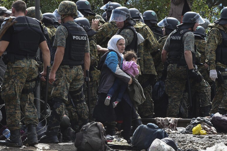 Una migrante con il suo bebe ' in braccio attraversa il cordone dell 'esercito macedone al confine con la Grecia, una delle foto dell 'ANSA esposte alla mostra  'Donne in marcia ' a Firenze -     RIPRODUZIONE RISERVATA