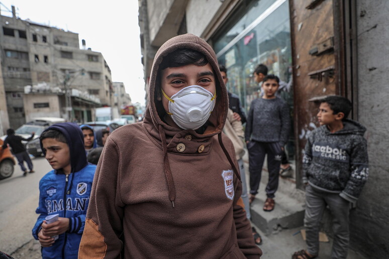 Ragazzini con le mascherine nelle strade di Gaza © ANSA/EPA
