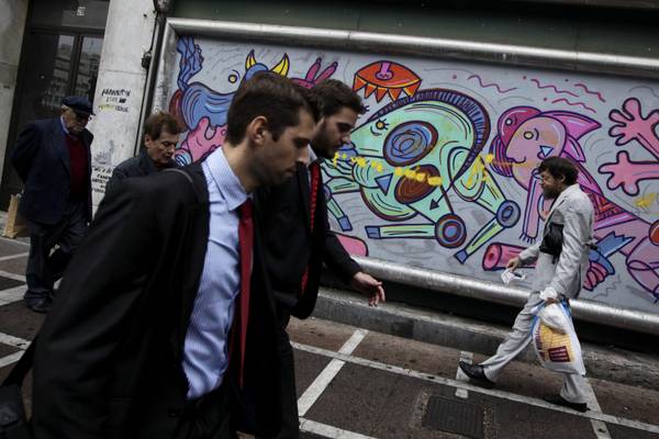 People walk past a graffiti in central Athens