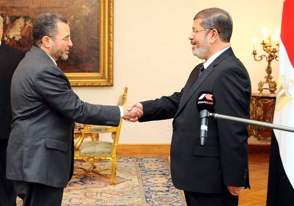 Il presidente egiziano Mohamed Morsi (d) stringe la mano al neo premier Hisham Qandil (s)