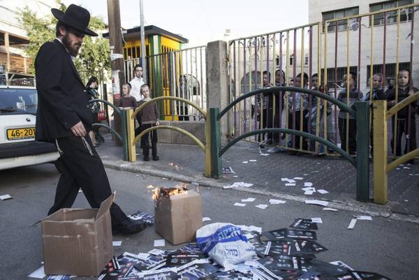 An Ultra-Orthodox Jewish man kicks a burning box with leaflets outside a Yeshiva  (religious school) on election day in Bnei Brak, outside Tel Aviv
