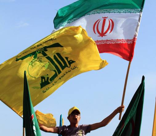 Un sostenitore di Hezbollah sventola la bandiera del movimento con quella dell'Iran