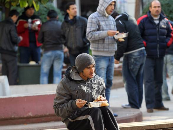 A young man is seen eating outside a soup kitchen in Athens, Greece
