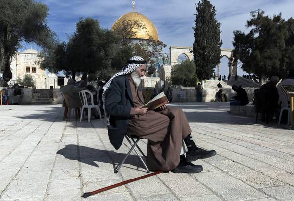The Dome of the Rock in the background as a Palestinian reads the  Koran in the al-Aqsa Mosque compound (file photo)