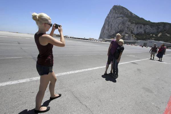 A tourist takes a picture with the Rock in the background at Gibraltar's airport