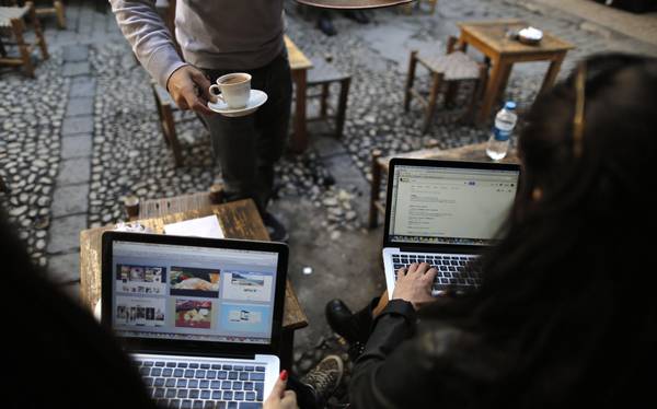 Turkish women check the Internet on their laptops while being served a coffee at a cafe in Istanbul, Turkey