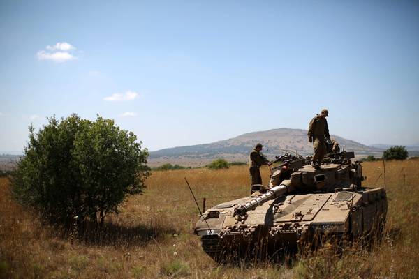 Israeli soldiers stand on top of a Merkava tank deployed on the Israeli-Syrian border