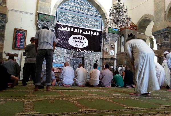 Worshipers pray at the Al-Noori Al-Kabeer mosque, next to flag used by the Islamic State in Mosul city