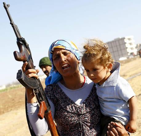A woman holds a gun near the Syria-Turkish border close to Kobani, Syria, near Sanliurfa city, Turkey